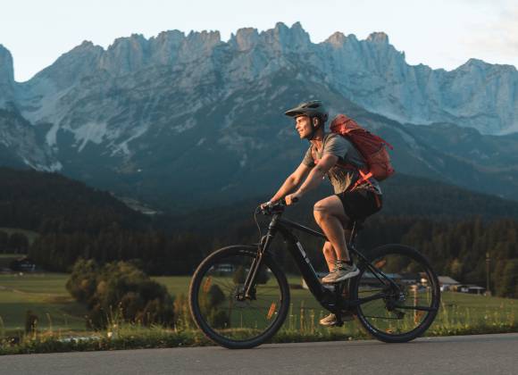 Mountainbiker fährt auf Straße am Wilden Kaiser